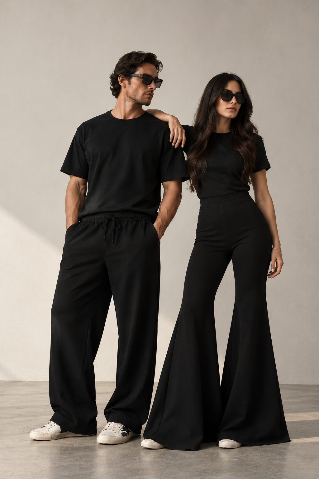 A man and a woman wearing the KŪRK black uniform in a warm, minimal architectural setting